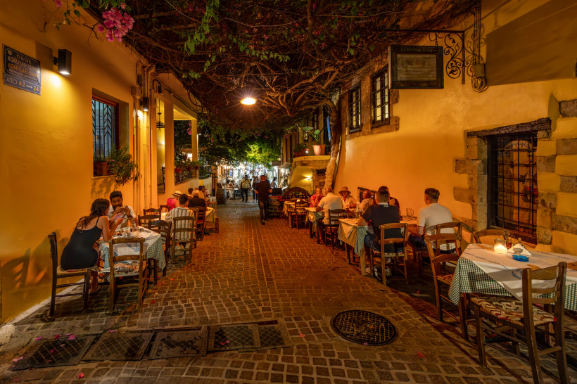 Belebte Gasse bei Nacht mit Außengastronomie und warm beleuchteten Hausfassaden