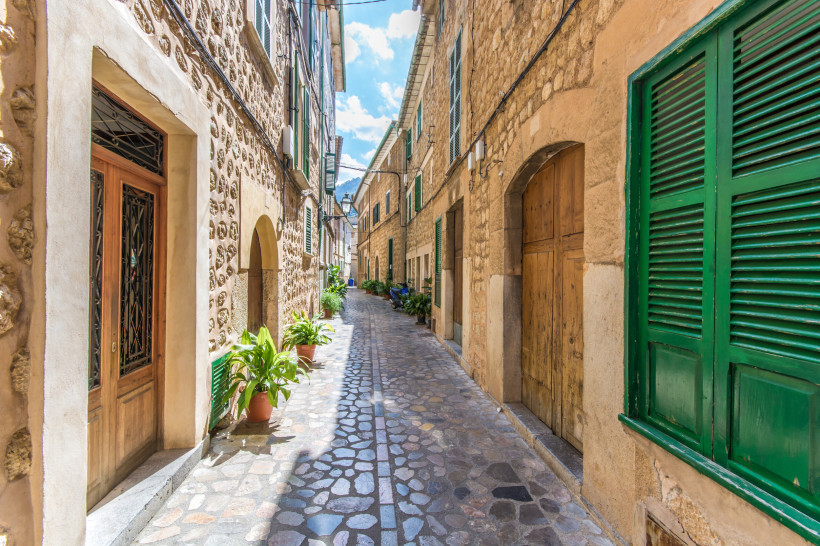 Schmale Gasse in der Altstadt von Sóller mit Natursteinpflaster, Steinhäusern und grünen Fensterläden