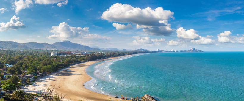 Hua Hin Beach – Weite Küstenlandschaft mit Meerblick Panorama des langen Sandstrandes von Hua Hin mit Blick auf das blaue Meer, Palmen und die Bergkulisse am Golf von Thailand