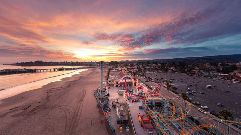 Sonnenuntergang über Küsten-Freizeitpark und Strand – Traumhafte Abendstimmung an der Küste Panorama eines Freizeitparks direkt am Sandstrand bei farbenprächtigem Sonnenuntergang, mit Promenade, Fahrgeschäften und breiter Küstenlinie – eindrucksvolle Abendstimmung am Meer.