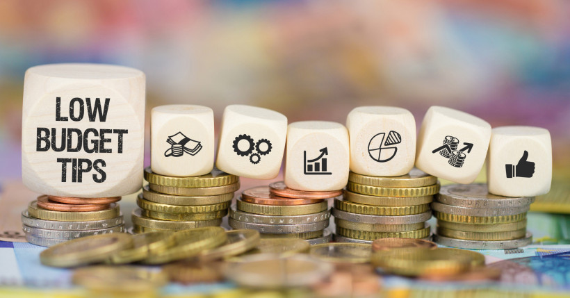 Günstig Reisen – Low-Budget-Tipps für Urlaub mit kleinem Geldbeutel Holzwürfel mit „Low Budget Tips“ auf Münzen als Symbol für günstige Reisen und Urlaub mit kleinem Budget