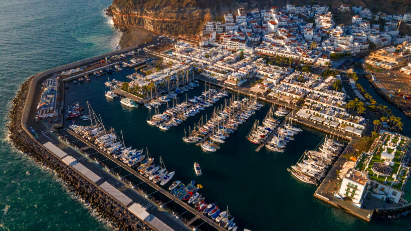 Marina Puerto de Mogán mit Liegeplätzen und Uferbebauung Luftaufnahme der Marina Puerto de Mogán mit Segelbooten, Hafenbecken und weißen Häusern am Ufer