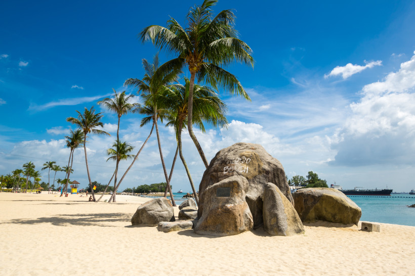 Siloso Beach auf Sentosa Island, Singapur Siloso Beach auf Sentosa Island in Singapur mit weißen Sandstränden, Palmen und Blick auf Frachtschiffe im Meer.