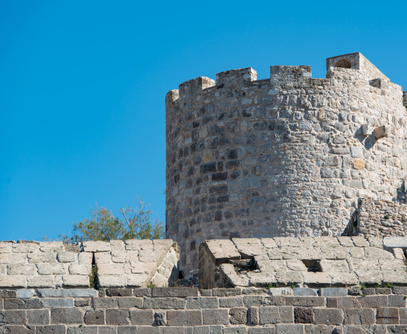 Detailansicht eines steinernen Turms und der Festungsmauer der Burg von Bodrum vor blauem Himmel
