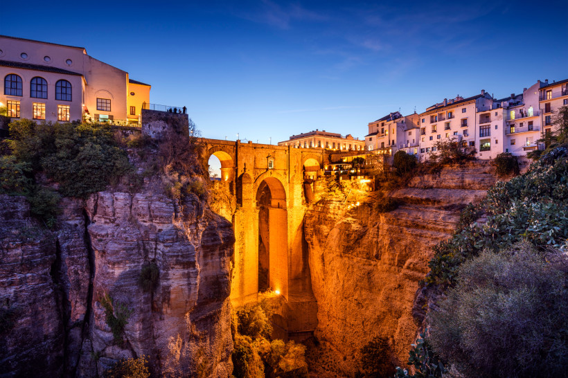Puente Nuevo in Ronda bei Dämmerung, beleuchtete Steinbrücke über einer tiefen Schlucht