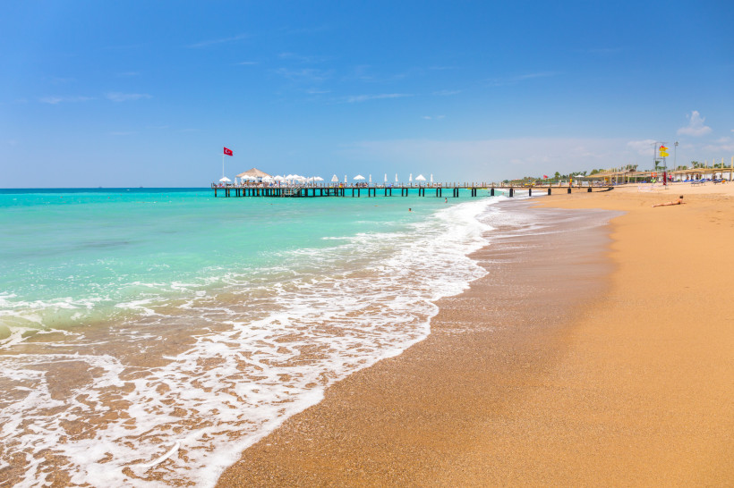 Feinsandiger Strand in Side mit Badesteg, türkisfarbenem Wasser und flach abfallender Küste – ideal für Strandurlaub in der Türkei