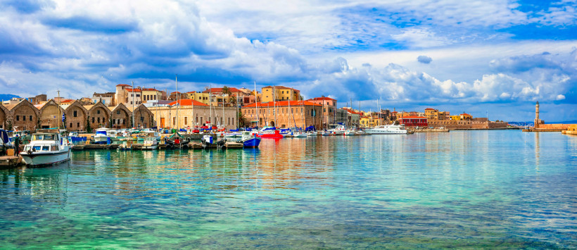 Hafen von Chania mit Segelbooten und Uferbebauung unter bewölktem Himmel