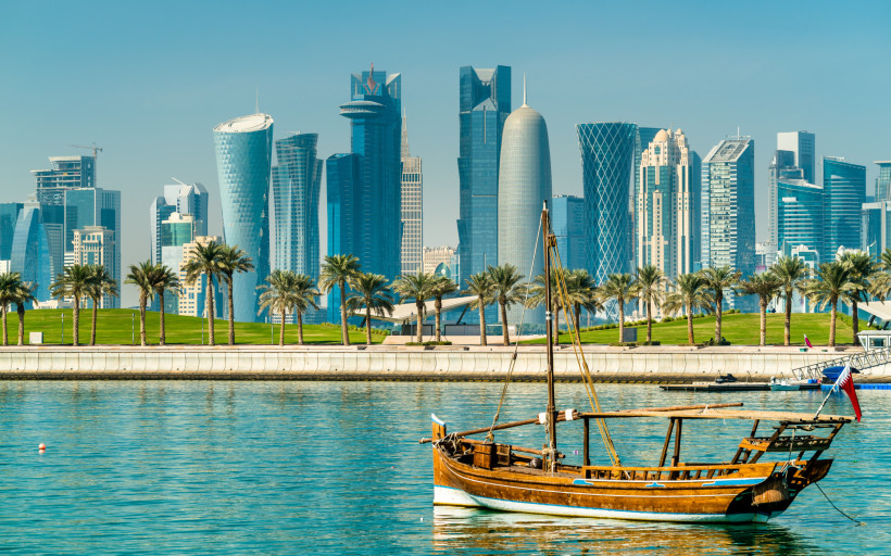 Skyline von Doha in Katar mit traditionellem Boot im Vordergrund – modernes Reiseziel für luxuriösen All Inclusive Urlaub im Orient