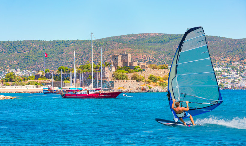 Windsurfer vor der Küste von Bodrum mit Blick auf Yachthafen und historische Burg an der türkischen Ägäis