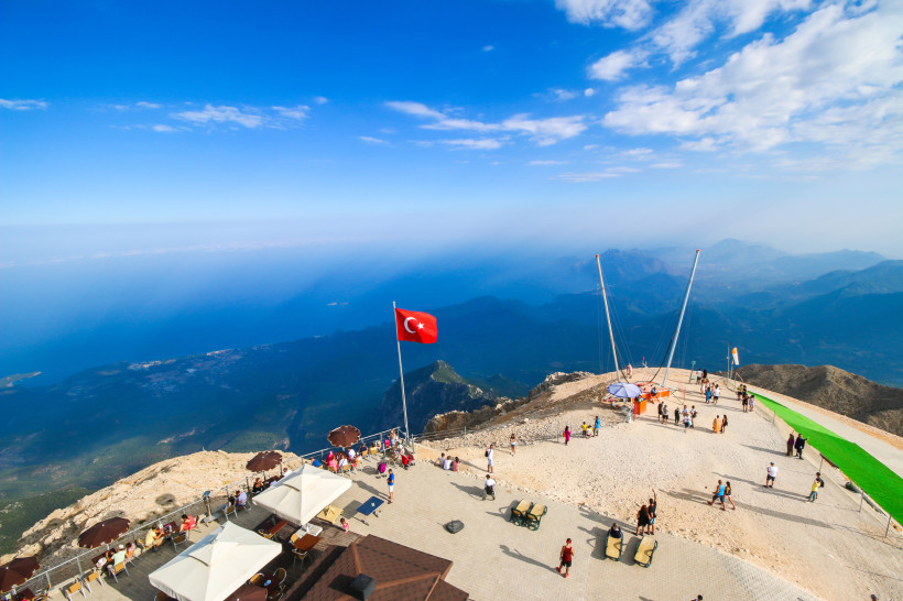 Tahtali-Berg Olympos – Gipfelblick mit Seilbahn über Antalya Aussichtsplattform auf dem Gipfel des Tahtalı-Bergs mit Seilbahn, türkischer Flagge und Panoramablick über Antalya und das Mittelmeer