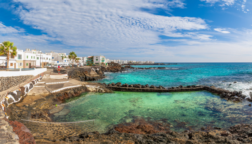 Küstenort Punta Mujeres auf Lanzarote mit weißer Bebauung, Lavaküste und natürlichem Meerwasserbecken