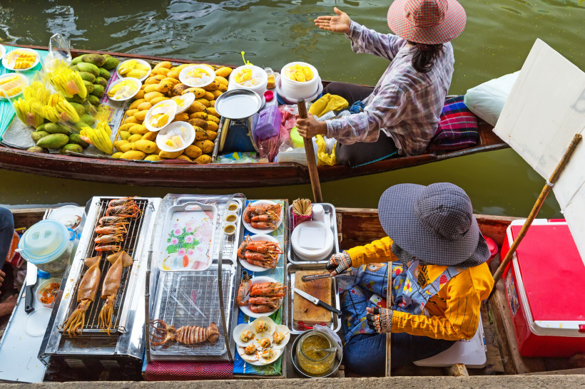 Damnoen Saduak Floating Market – Streetfood Frisches Obst und gegrillte Meeresfrüchte auf Händlerbooten am Damnoen Saduak Floating Market in Thailand.