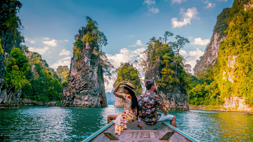 Paar auf einem Longtail Boot im Khao Sok Nationalpark zwischen steilen Karstfelsen und türkisblauem Wasser