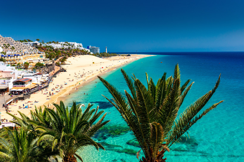 Sommer auf Fuerteventura – Sonne, Strand und traumhafte Badebedingungen Sonniger Strand von Morro Jable auf Fuerteventura mit türkisblauem Meer und Palmen – perfektes Sommerwetter für Badeurlaub und Wassersport.