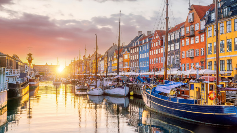 Nyhavn in Kopenhagen mit bunten Häuserfassaden, Segelbooten im Hafenbecken und Abendlicht