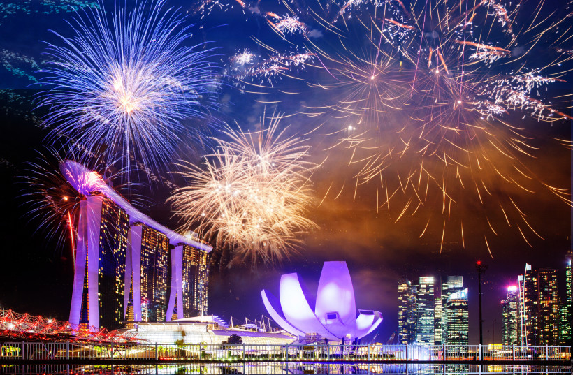 Singapur Farbenfrohes Feuerwerk über Marina Bay Sands und dem ArtScience Museum in Singapur. Die markanten Gebäude sind hell beleuchtet und spiegeln sich im Wasser der Bucht.