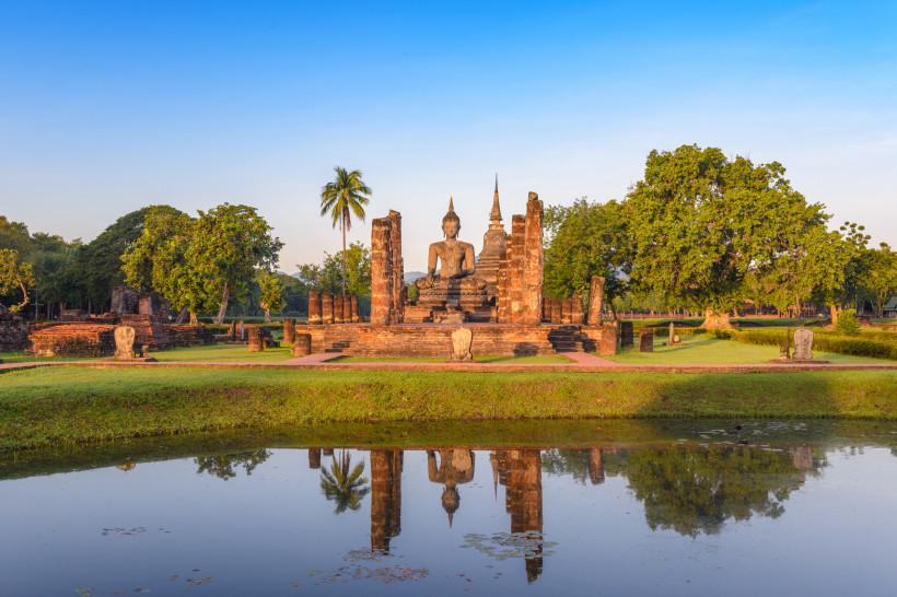 Buddha-Statue und antike Tempelruinen im Wat Mahathat in Sukhothai Historical Park, Thailand