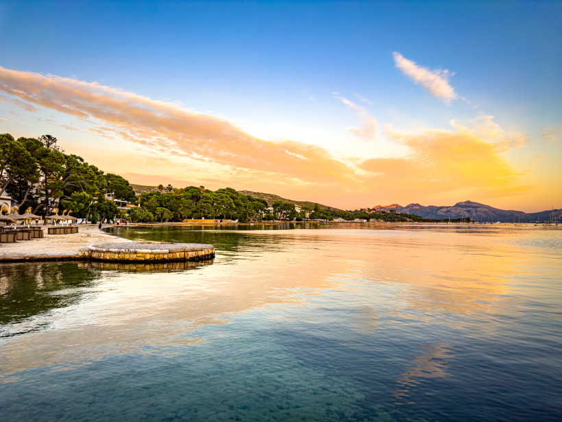 Uferpromenade Pine Walk in Port de Pollença mit ruhiger Bucht, Strand und Pinien bei Abendlicht