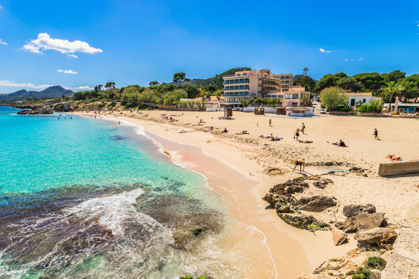 Son Moll Strand in Cala Ratjada auf Mallorca mit hellem Sand, Felsen am Ufer und kristallklarem Wasser – ideal für Badeurlaub und Strandferien