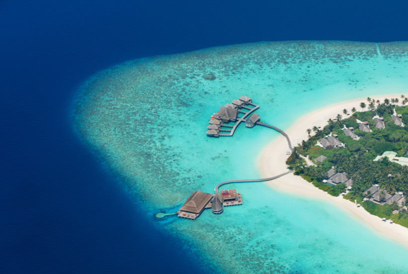 Malediven - Raa-Atoll Exklusive Overwater-Villen auf den Malediven, verbunden durch Stege mit einer luxuriösen Resort-Insel mit Palmenstrand und türkisfarbenem Wasser.
