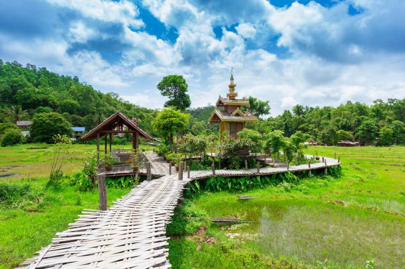 Traditionelle Bambusbrücke mit kleinem Tempel und Reisfeldern in Pai, Nordthailand