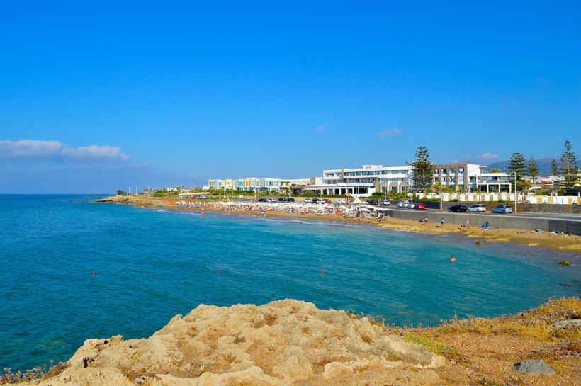 Küstenabschnitt und Strand in Kato Gouves mit türkisfarbenem Meer und Hotelgebäuden im Hintergrund