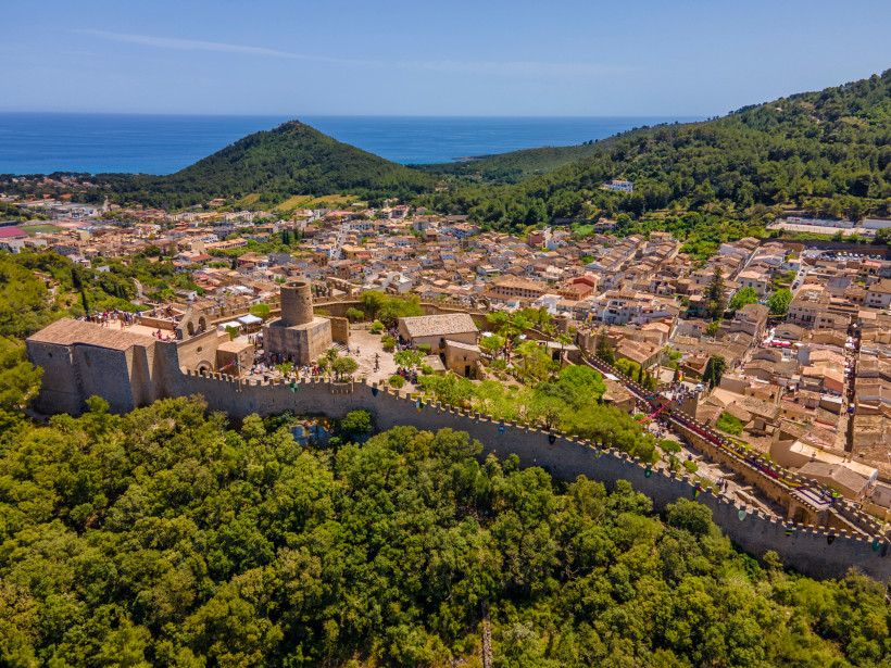 Blick auf die Burg von Capdepera mit Stadt, Hügeln und Meer im Hintergrund