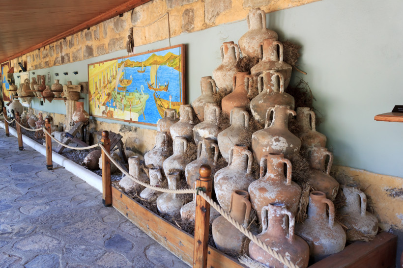 Sammlung antiker Amphoren aus Ton in einer historischen Ausstellung, gestapelt entlang einer Steinwand