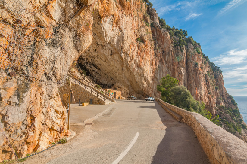 Eingang der Coves d’Artà an einer Felswand mit Zufahrtsstraße und Treppenaufgang