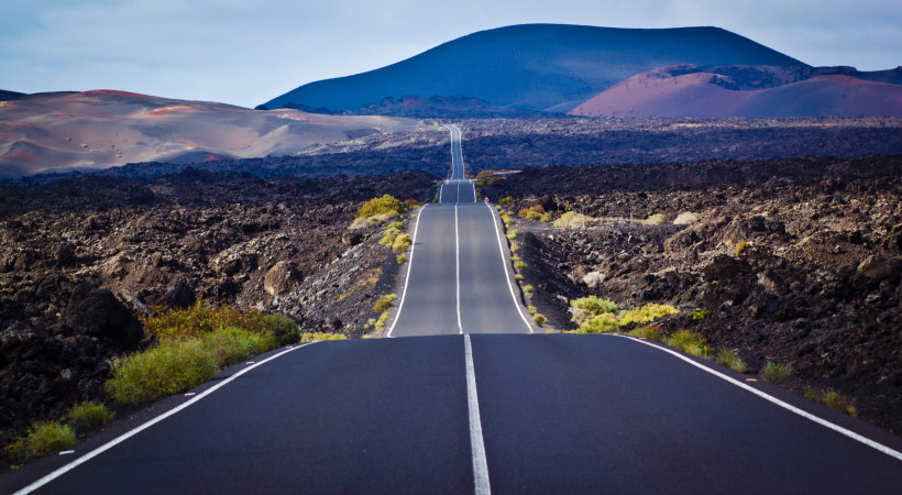 Timanfaya Nationalpark Lanzarote – Straße durch die spektakuläre Vulkanlandschaft Asphaltstraße im Timanfaya Nationalpark auf Lanzarote, umgeben von schwarzen Lavafeldern und Vulkanlandschaft.