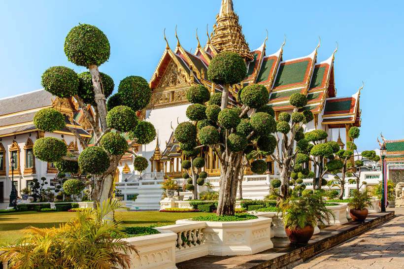 Königspalast Bangkok – Gartenanlage mit kunstvoll geschnittenen Bäumen Kunstvoll geschnittene Bäume vor dem Königspalast in Bangkok, Thailand – traditionelle Architektur und gepflegte Gartenanlage.