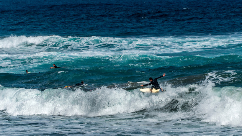 Surfer auf einer brechenden Welle am Strand La Cícer