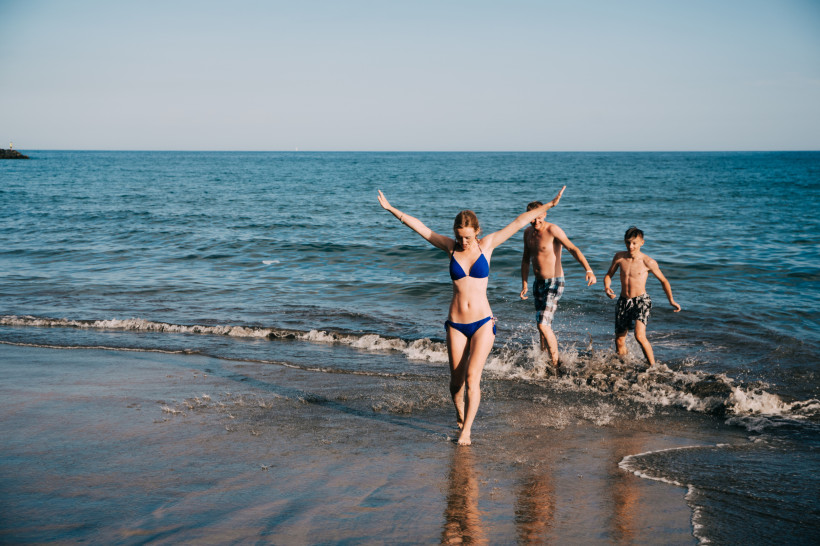 Badevergnügen am Strand von Gran Canaria Eine Frau und zwei Jungen genießen das warme Wasser am Strand von Gran Canaria. Die Sonne scheint, das Meer glitzert – perfekter Badespaß für Familien und Freunde.