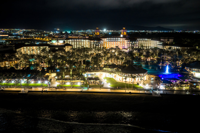 Nachtaufnahme des Hotelbereichs Villa del Conde mit beleuchteter Anlage, Palmen und Pool am Strand