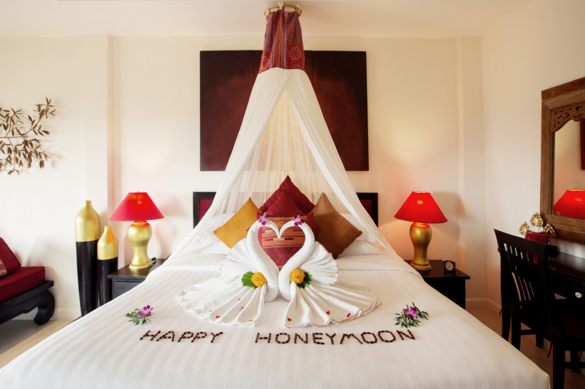 Liebevoll dekoriertes Zimmer für Honeymooner Ein romantisch geschmücktes Hotelzimmer mit Handtuch-Schwänen in Herzform, Blüten und dem Schriftzug „Happy Honeymoon“ auf dem Bett – perfekt für frisch Verliebte oder Paare auf Hochzeitsreise.