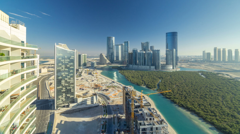 Luftaufnahme von Abu Dhabi mit modernen Hochhäusern, Mangrovenwald und türkisblauen Wasserkanälen