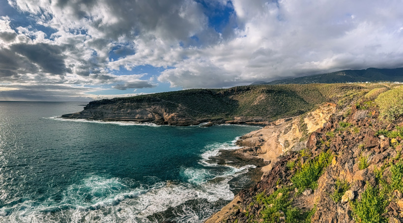 La Caleta: Blick auf die felsige Küstenlinie und das Meer Felsige Küste von La Caleta mit Meeresbrandung und bewölktem Himmel