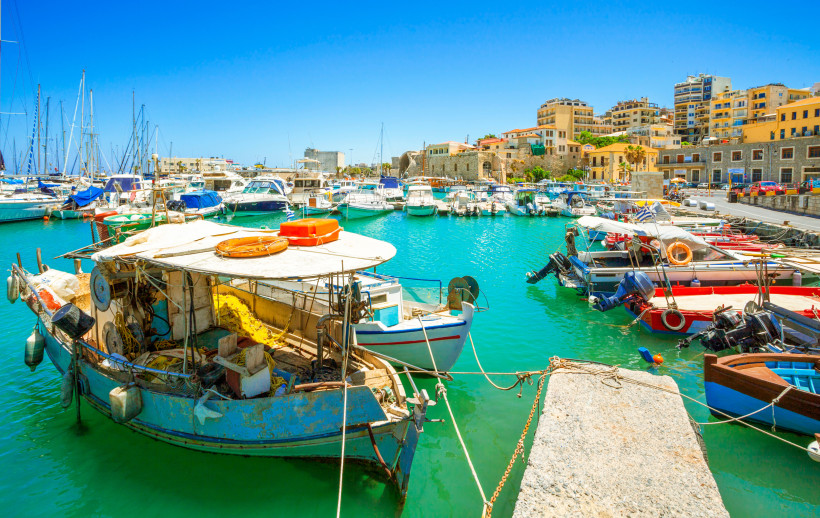 Hafenbecken in Heraklion mit Booten und Uferbebauung Hafen von Heraklion mit Fischerbooten und Yachten im türkisfarbenen Wasser, im Hintergrund Gebäude am Ufer