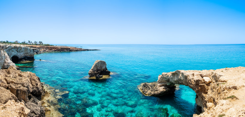 Natürliche Felsbrücke bei Kap Greco (Love Bridge) über klarem, türkisfarbenem Meer; Küstenpanorama Zyperns.