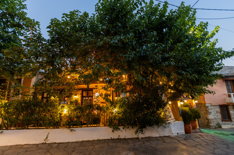 Beleuchteter Innenhof in Kokkin Hani mit großem Baum und Sitzbereich am Abend