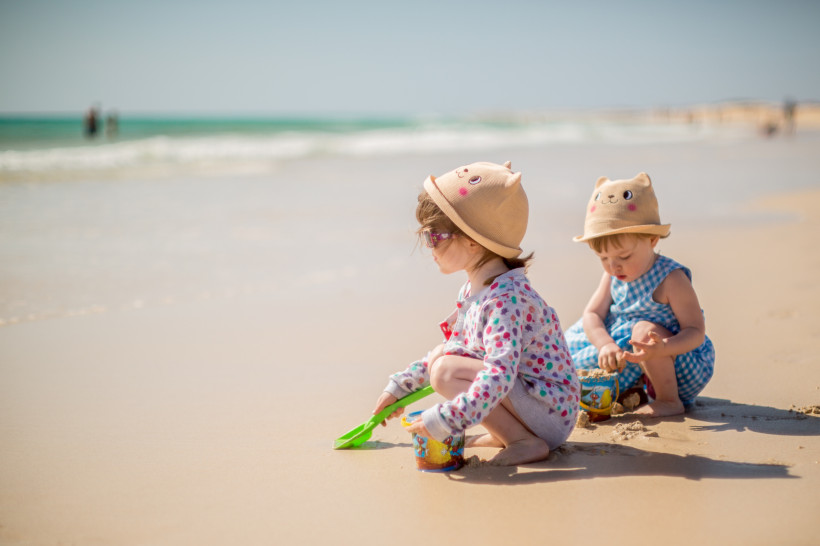 Zwei Kinder spielen am Strand von Fuerteventura im Sand und genießen den sonnigen Urlaubstag