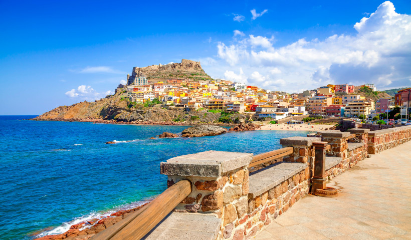 Blick auf Castelsardo an der Nordküste Sardiniens mit bunten Häusern, Burg und tiefblauem Meer – einer der schönsten Orte der Insel