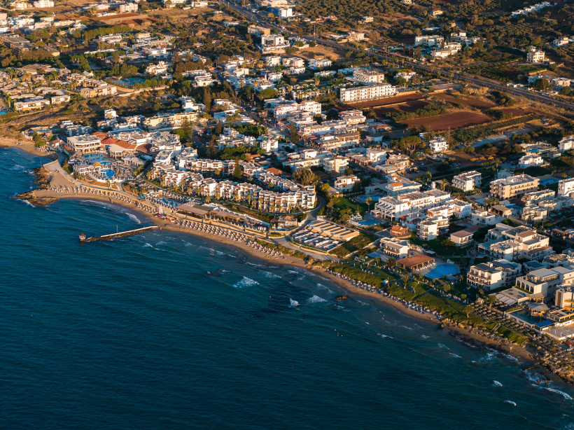 Luftaufnahme der Küste von Stalida mit Strand, Hotels und Bebauung entlang der Bucht