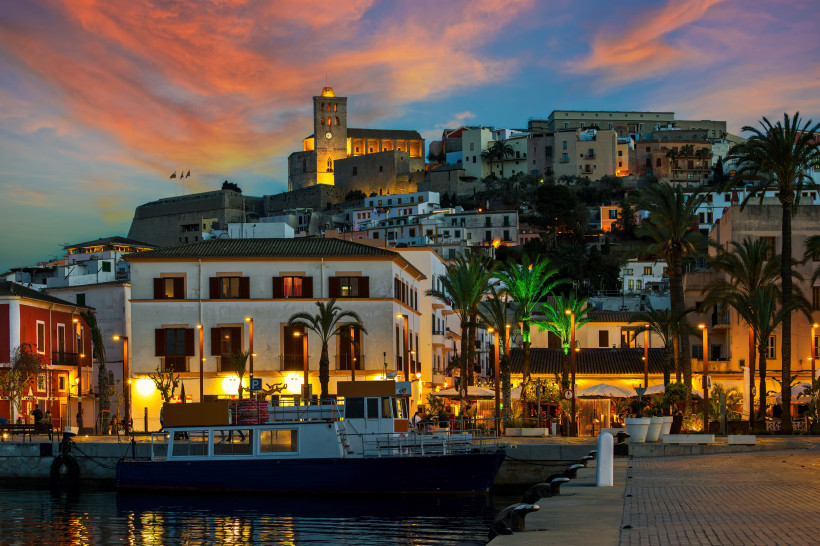 Abendstimmung in Eivissa auf Ibiza mit Hafen, Booten und beleuchteter Altstadt unter farbigem Himmel