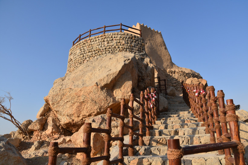 Steintreppe mit Holzgeländern führt zum Dhaya Fort in Ras Al Khaimah – historisches Wahrzeichen auf einem Hügel.