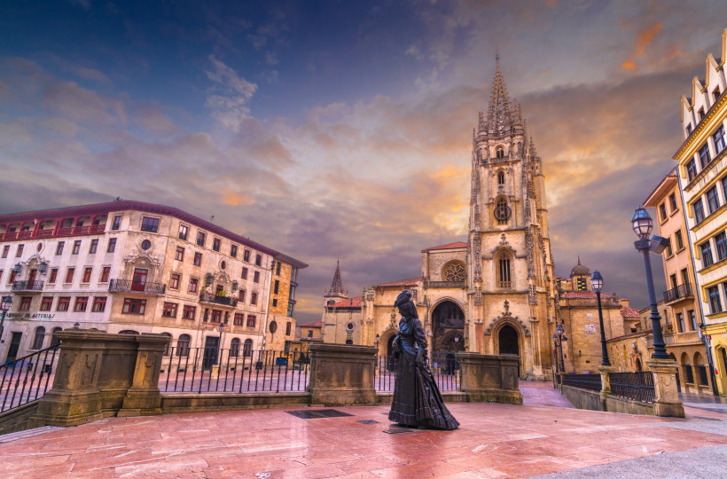 Blick auf die Kathedrale von Oviedo mit gotischem Turm und Statue auf dem Platz bei Abendlicht