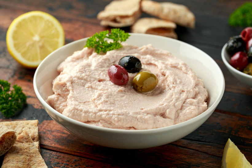 Schale mit Taramasalata, garniert mit Oliven und Petersilie, daneben Zitronenhälfte und Brot
