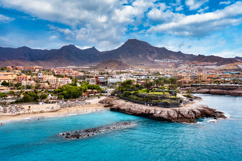 Küstenansicht von Adeje auf Teneriffa mit Strand, Felsen und Stadt vor Bergkulisse