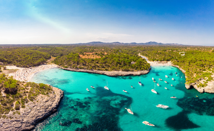 Badebucht auf Mallorca mit klarem Wasser, Felsen und Booten