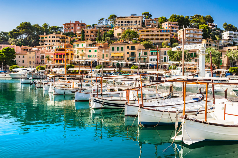 Hafen von Sóller, Mallorca Traditionelle Holzboote im Hafen von Port de Sóller auf Mallorca, vor farbenfrohen Gebäuden und grünen Hügeln